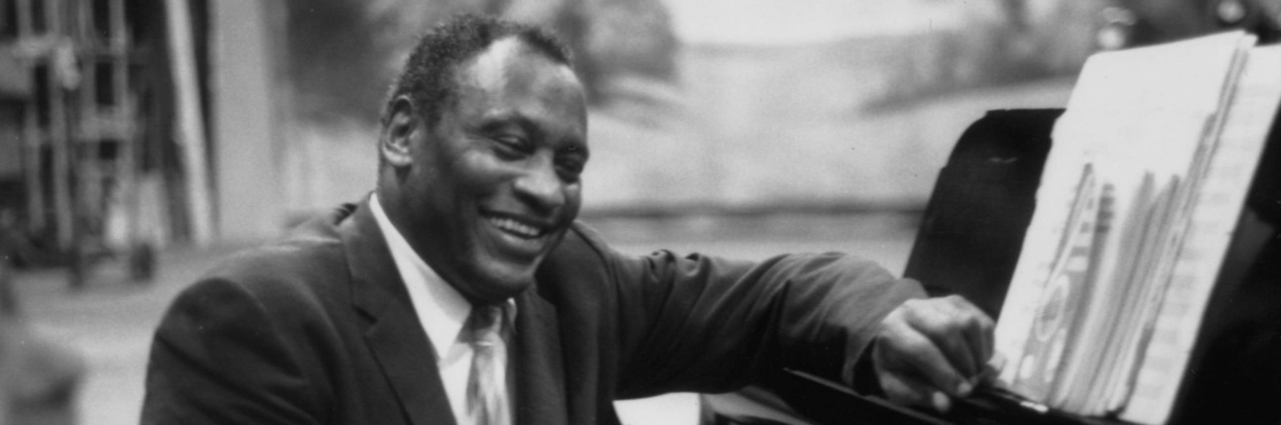 Paul Robeson smiling at piano with sheet music